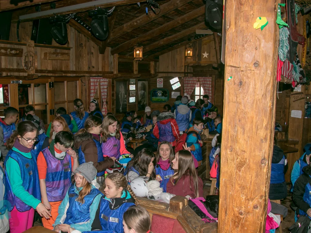 Große Gruppe in der holzvertäfelten Hütte.